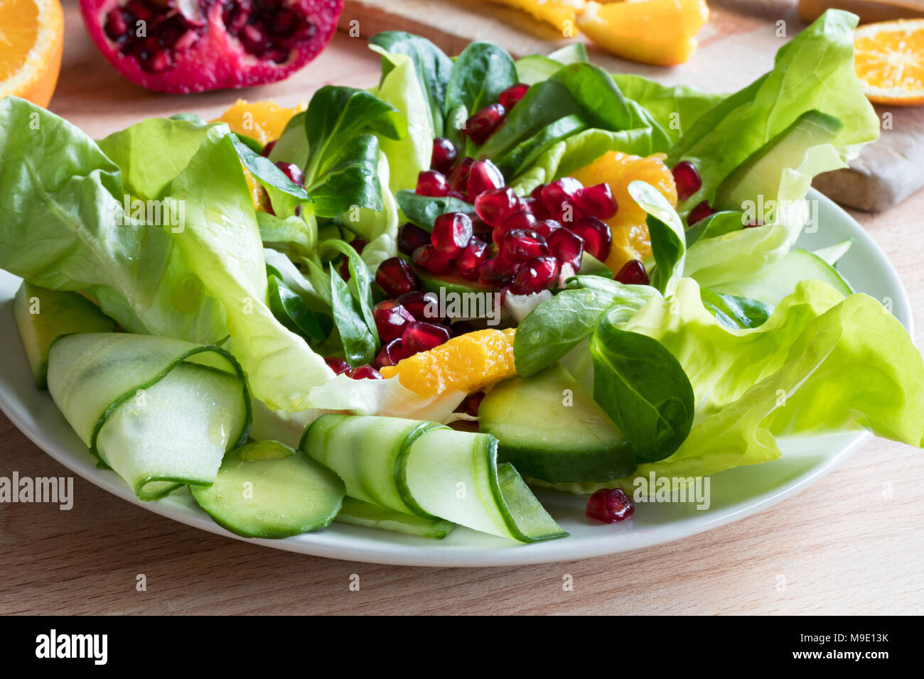 Insalata di verdure su una piastra - lattughe, lattughella, cetriolo, avocado, arancio, melograno Foto Stock