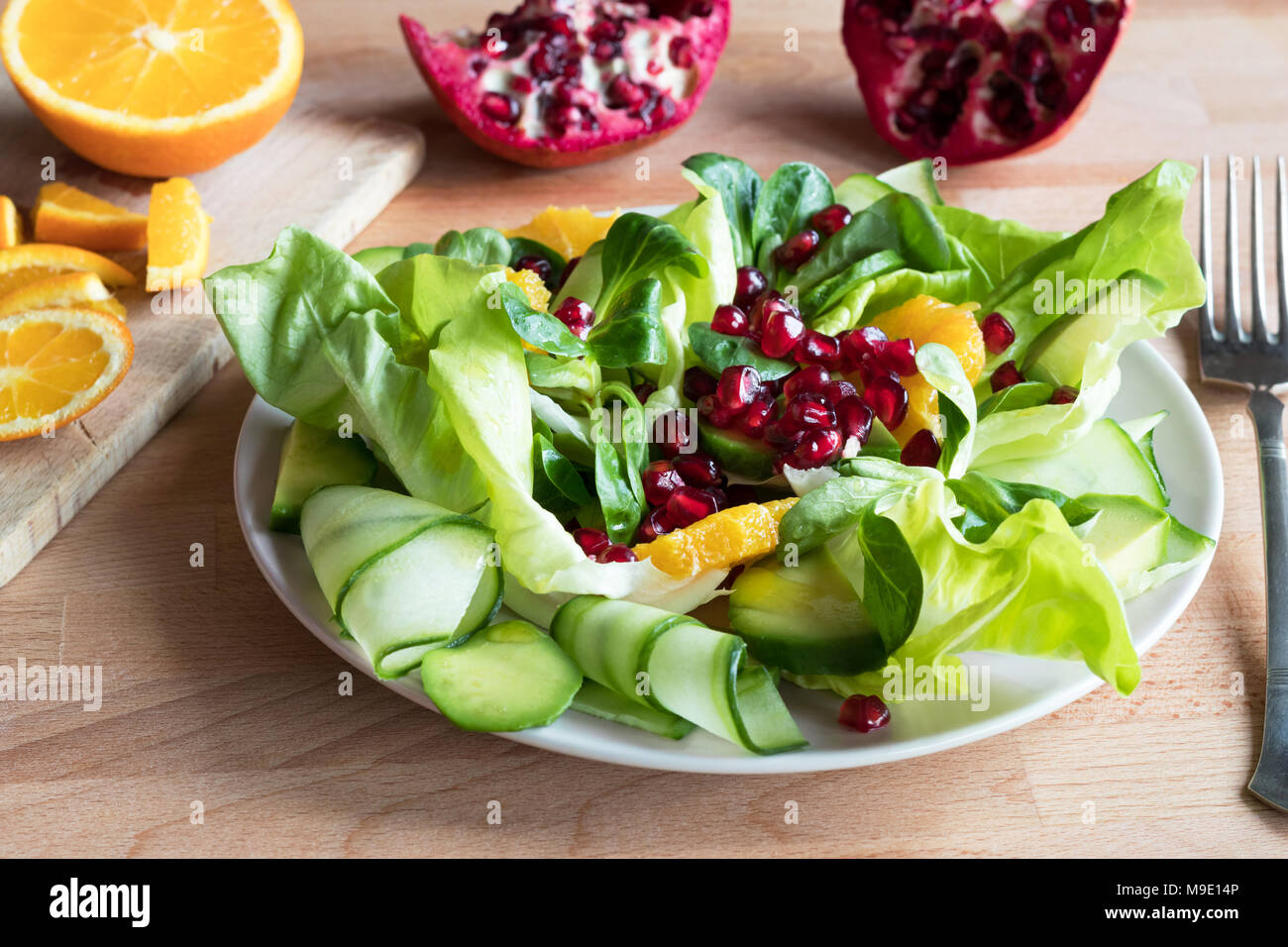 Insalata di verdure con lattuga, lattughella, cetriolo, avocado, arancione e i semi di melograno. Foto Stock