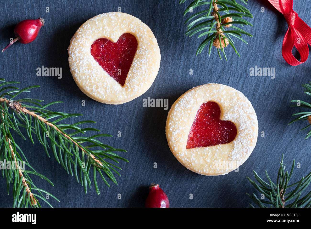 Sfondo di natale con due Linzer biscotti di Natale, essiccato, rosa canina e rami di abete rosso Foto Stock