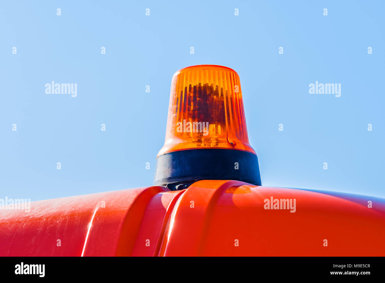 Lampeggiatore o una rotazione beakon di avvertimento di colore arancione contro lo sfondo del cielo blu chiaro Foto Stock