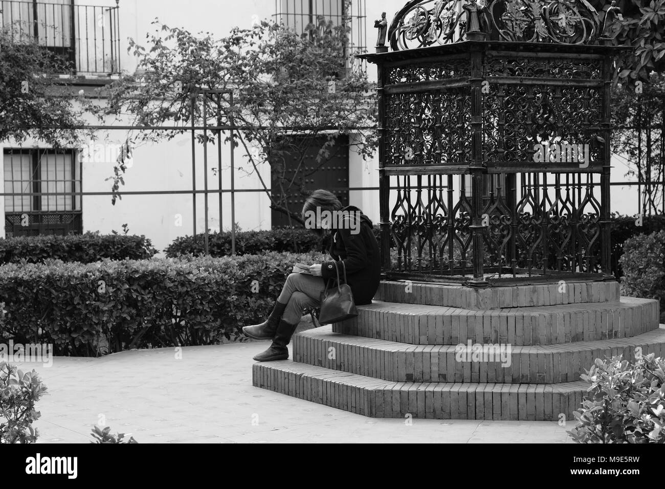 Donna sola lettura in una piccola piazza di Siviglia Foto Stock
