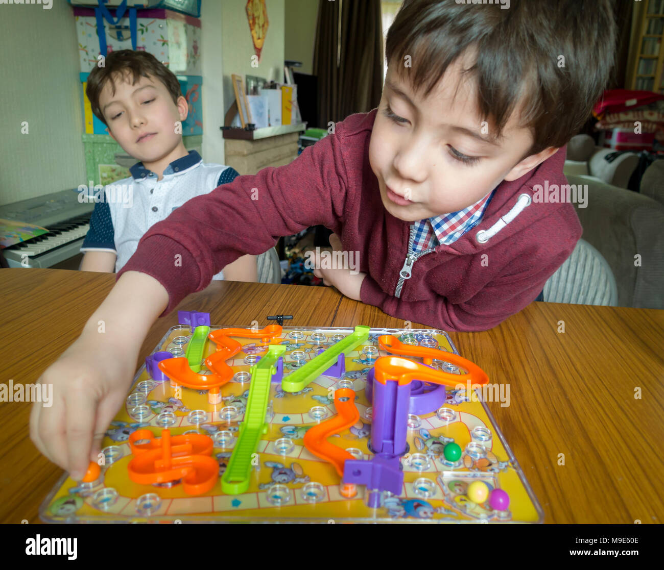 Due ragazzi la riproduzione di un gioco da tavolo di serpenti e scale Foto Stock