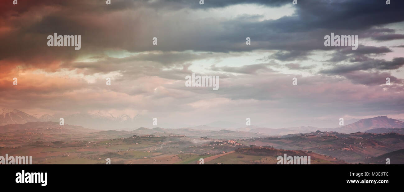 Italiano il paesaggio rurale. Provincia di Fermo, Italia. I villaggi e i campi su colline colorate sotto il cielo nuvoloso Foto Stock