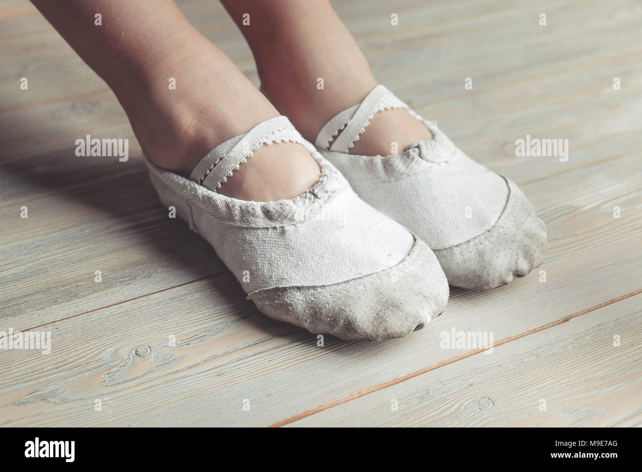 Un po' di ballerini. Le gambe di una ragazza nel balletto pantofole su un pavimento di legno Foto Stock