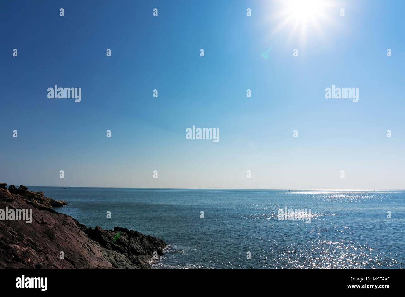 Paesaggio di mare azzurro e blu cielo con costa rocciosa Foto Stock
