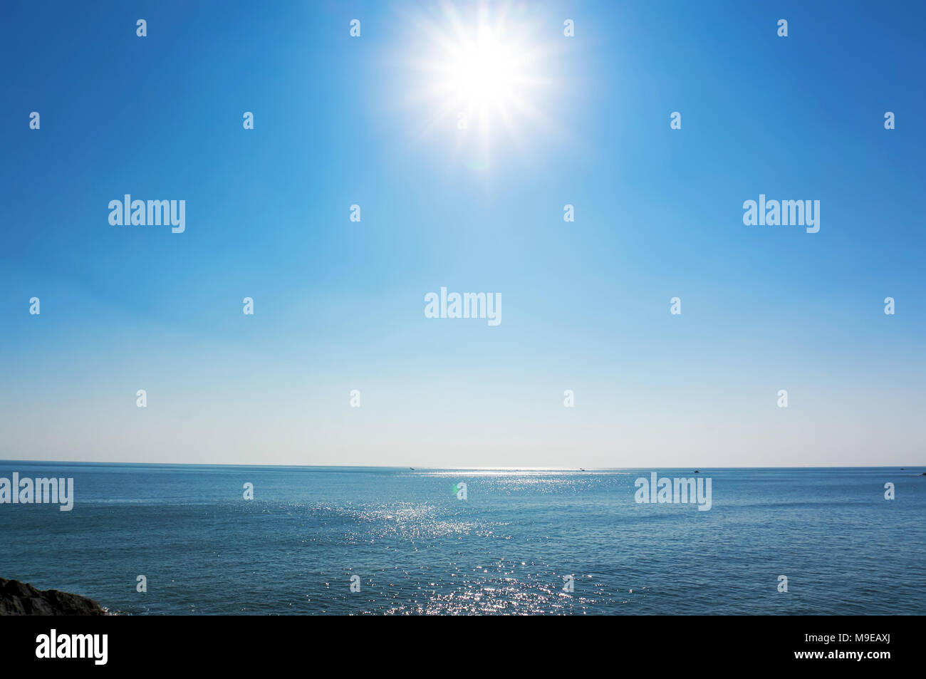 Il sole splende nel cielo blu sopra il mare blu. La linea di orizzonte del mare Foto Stock
