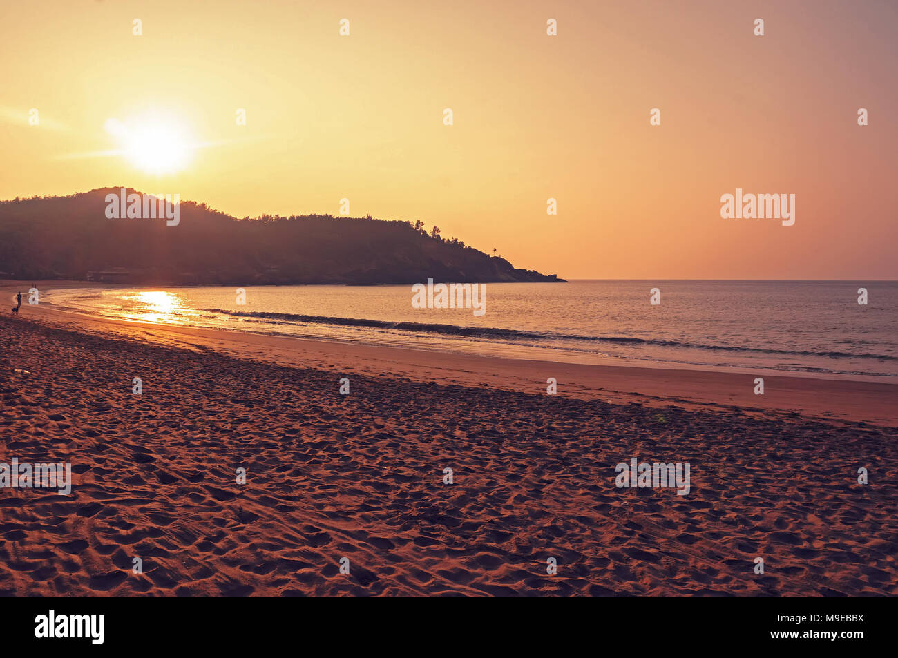 Il tramonto e il mare. India Gokarna. Il sole tramonta sul colle sul mare. Giallo sabbia calda in primo piano. Foto Stock