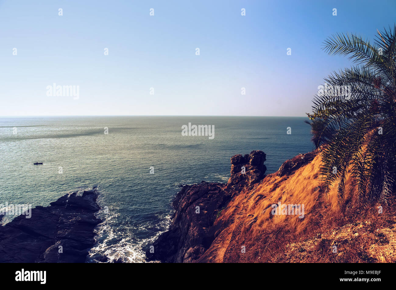 La ripida costa rocciosa con il blu del mare e le onde che si infrangono sulle rocce. Gokarna India Foto Stock