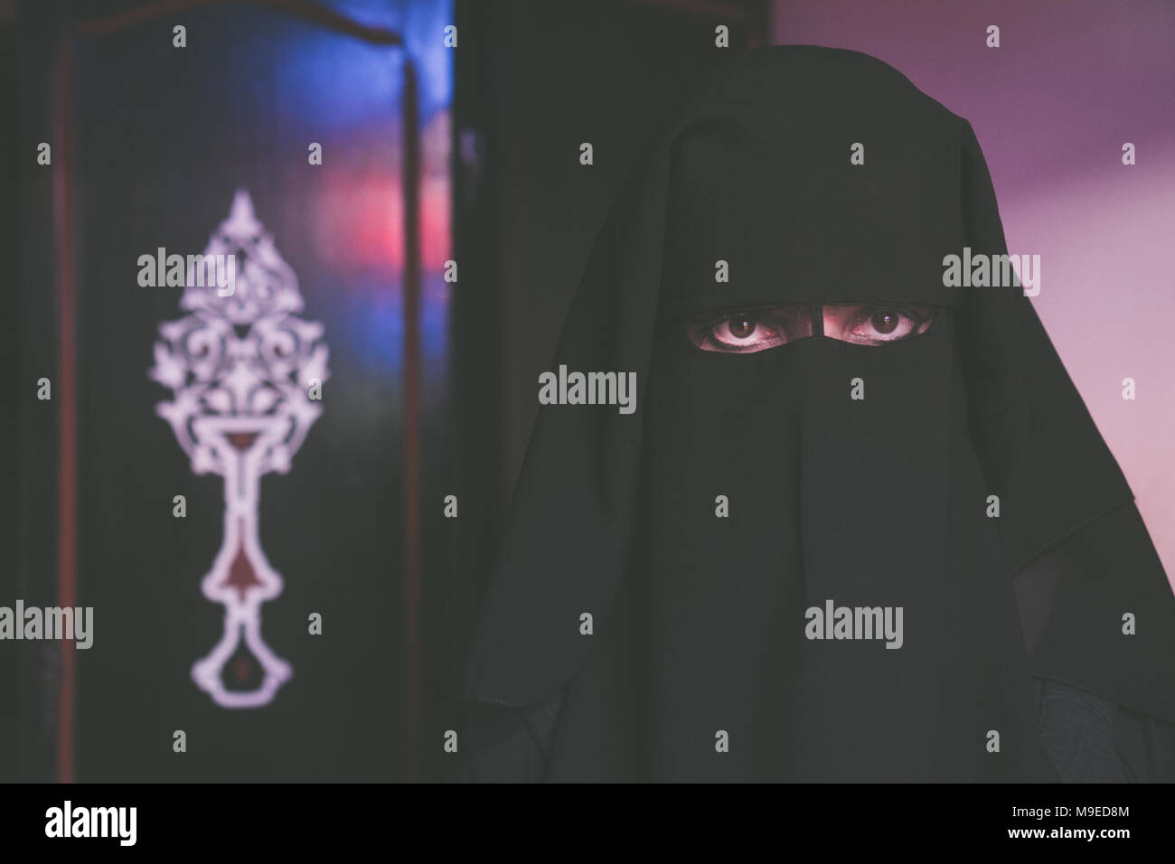 La donna araba in modesti vestiti di nero con la faccia coperta con niqab nero Foto Stock