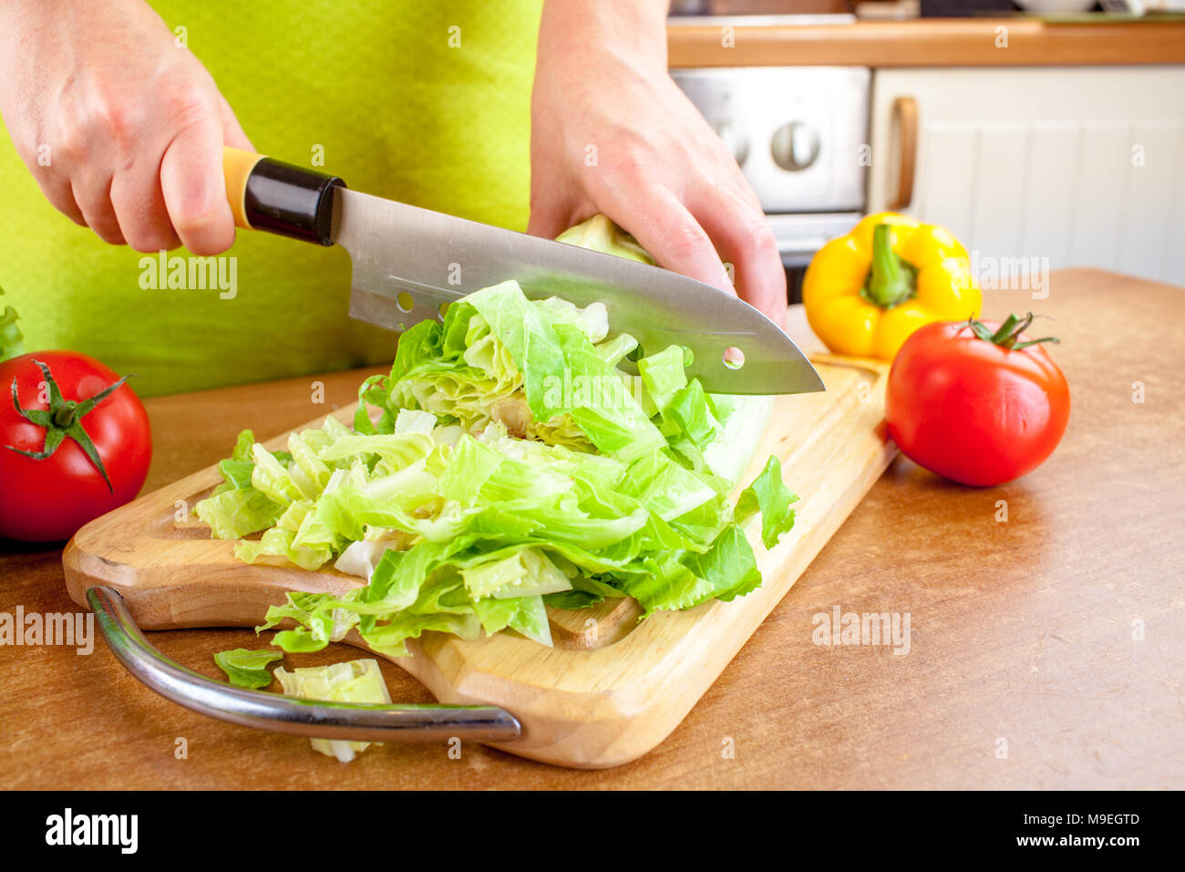 Donna con le mani in mano il taglio di lattuga, dietro di verdure fresche. Foto Stock