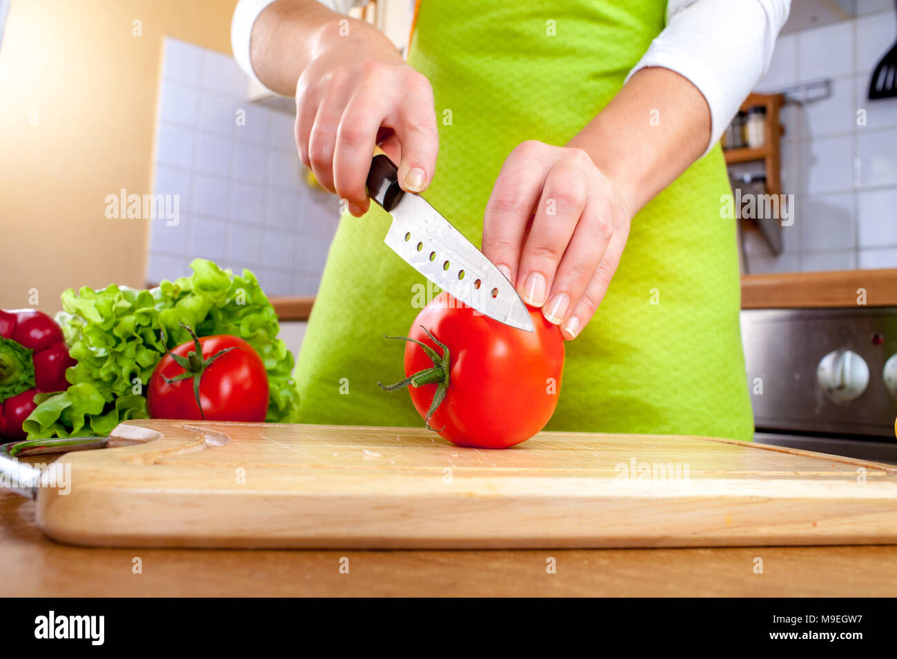 Donna con le mani in mano il taglio di pomodoro fresco su cucina Foto Stock