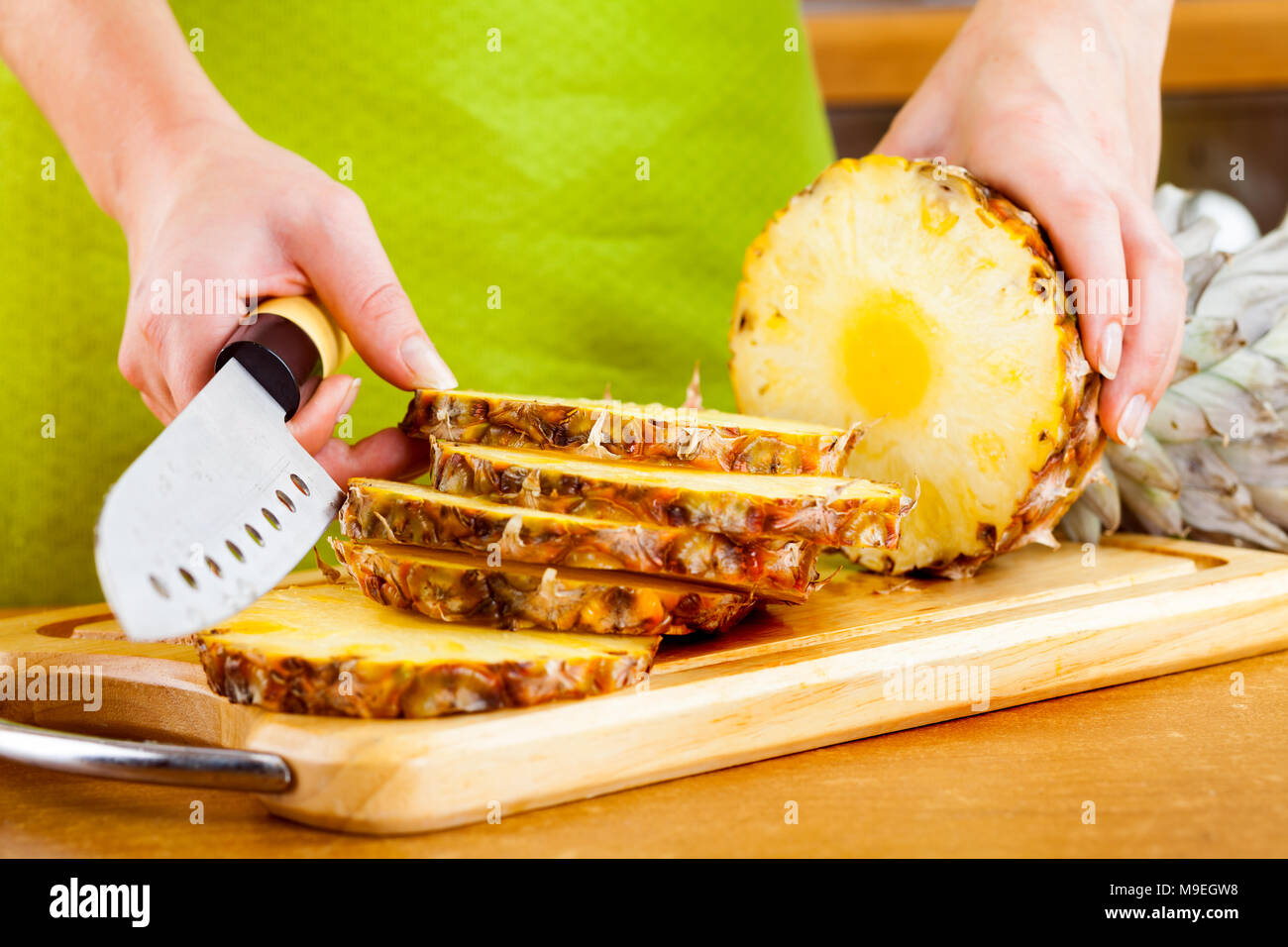 Donna con le mani in mano il taglio di ananas fresco su cucina Foto Stock
