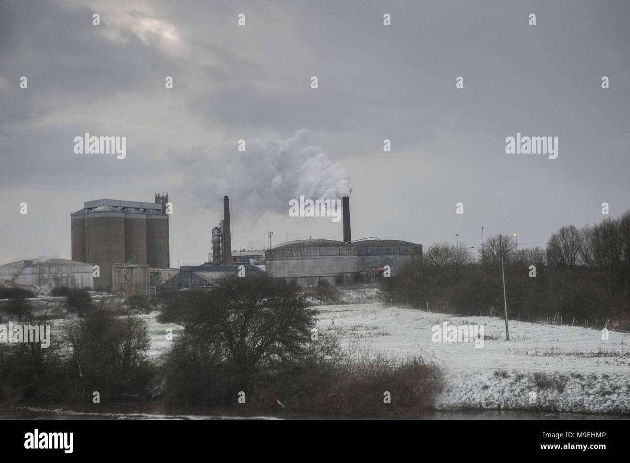 Campi innevati circondano una fabbrica il pompaggio di sostanze inquinanti nell' Foto Stock