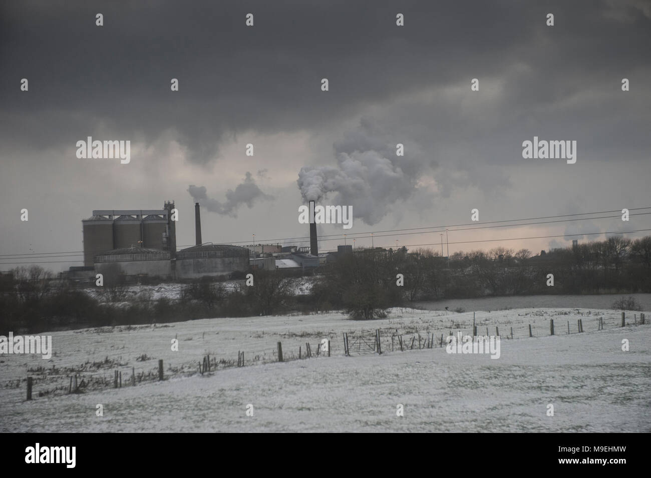 Campi innevati circondano una fabbrica il pompaggio di sostanze inquinanti nell' Foto Stock