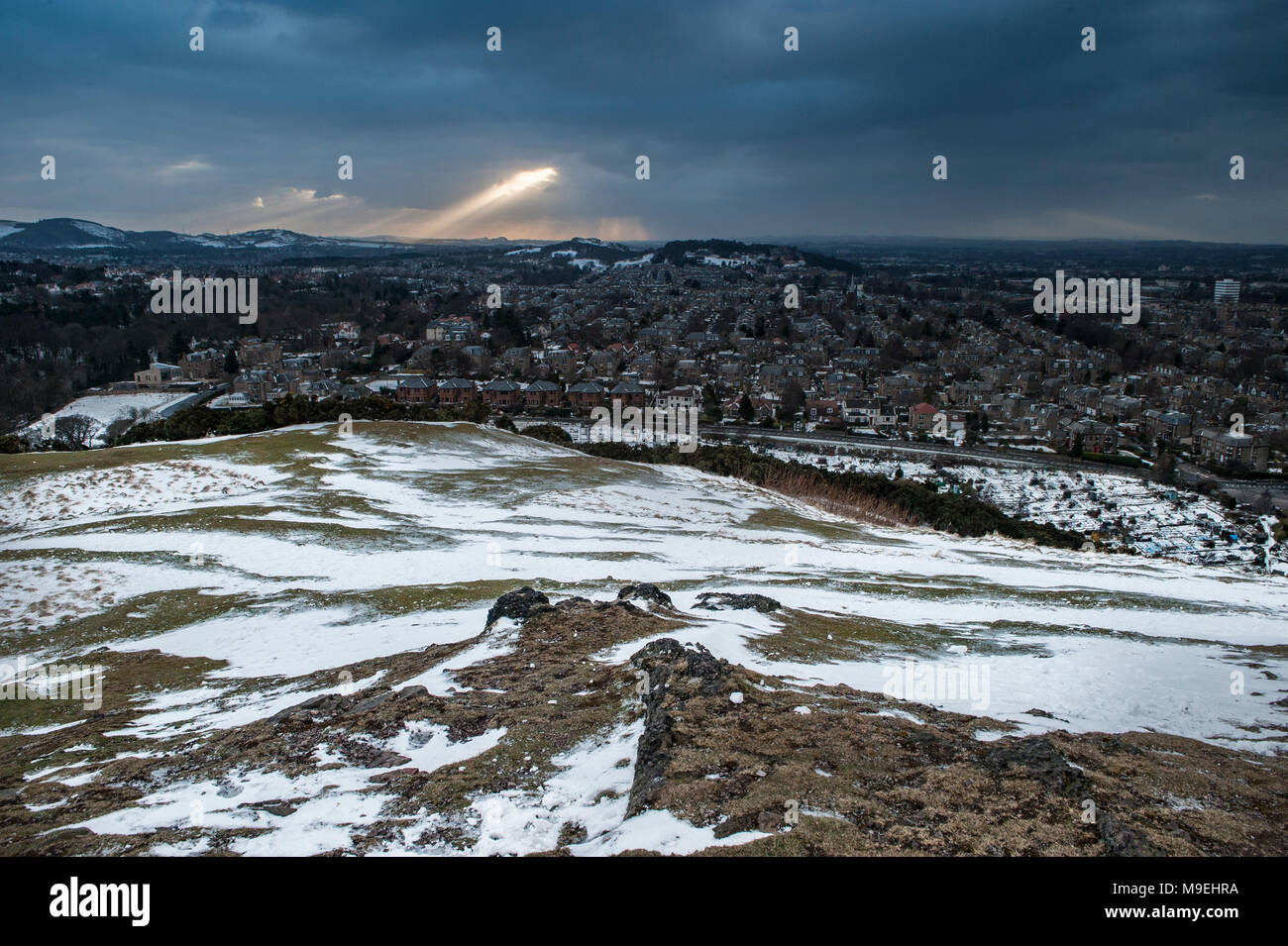 Una vista dall'alto sopra di Edimburgo in half light guardando ad ovest con raggi di luce attraverso la rottura delle pesanti nuvole nere Foto Stock