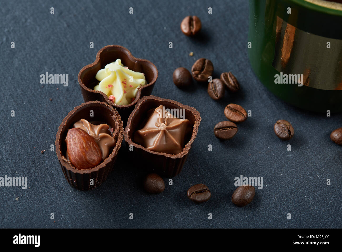 Tazza da caffè, caffè in grani, cioccolatini sul bordo di pietra su sfondo di legno, il fuoco selettivo di close-up. Studio shot. Deliziosa bevanda al mattino. Foto Stock