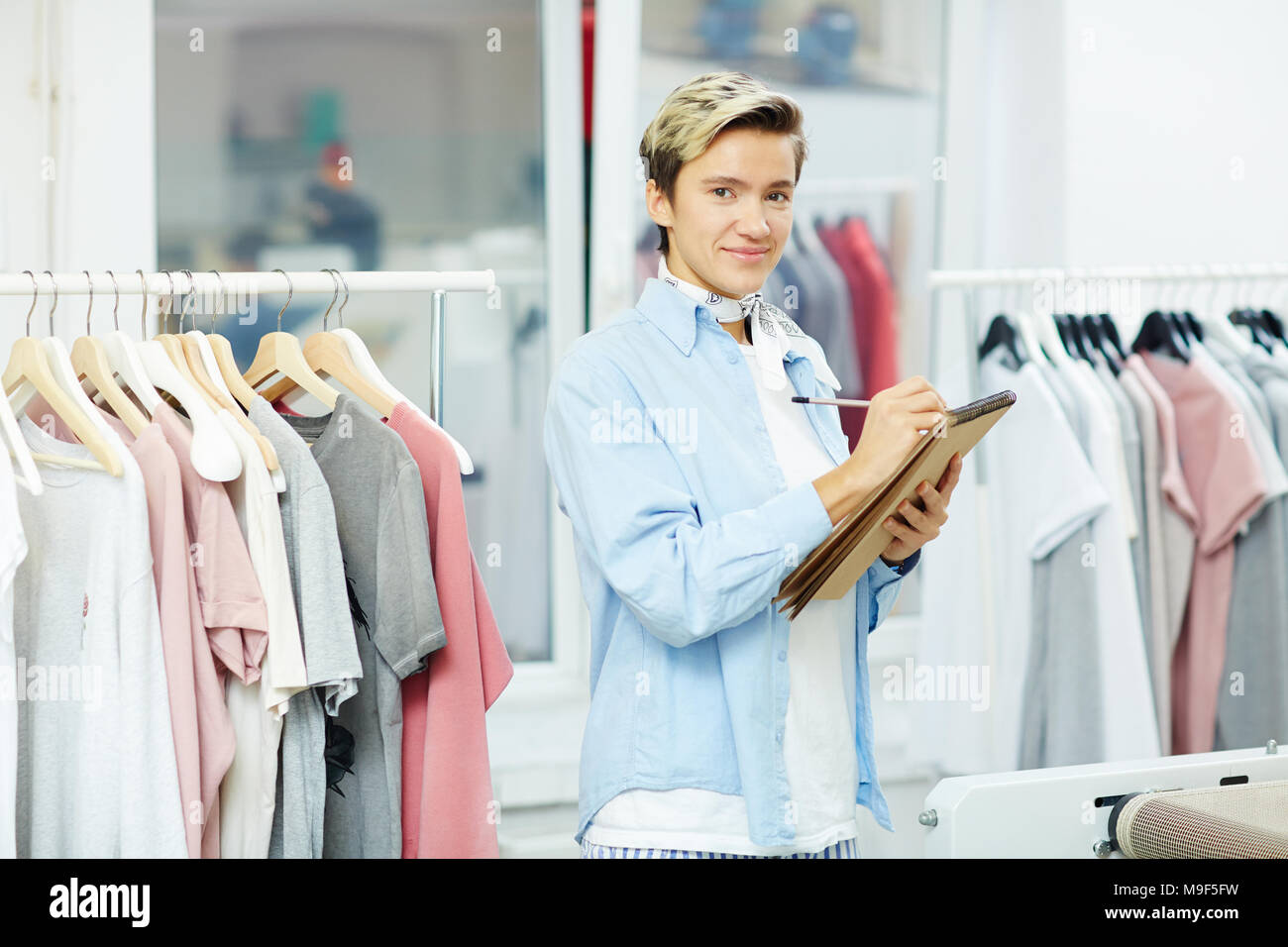Designer rendendo note in Blocco note nel suo studio Foto Stock