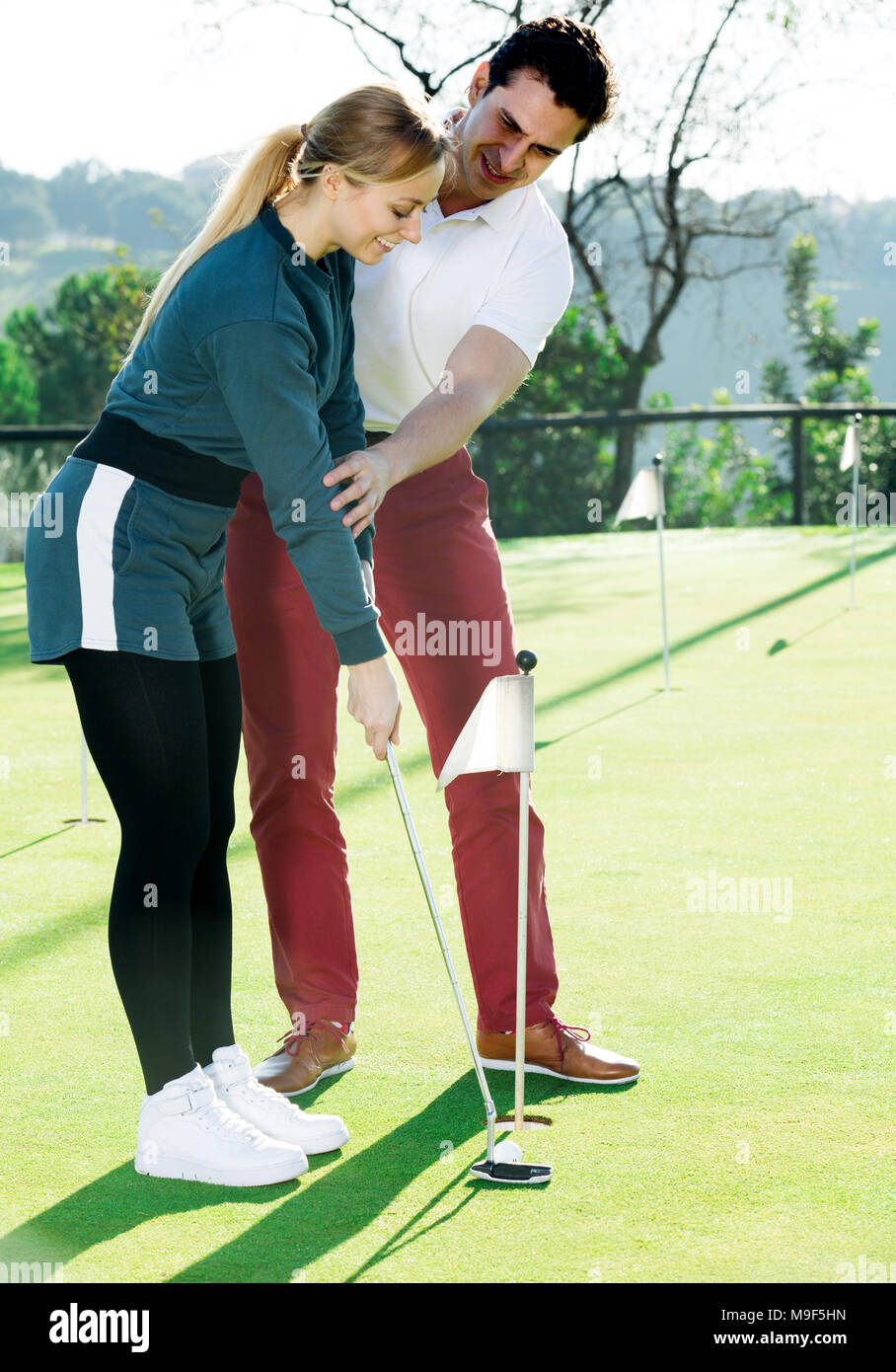 Maschio formatore di golf mostra giocatrice come colpire giustamente a sfera Foto Stock