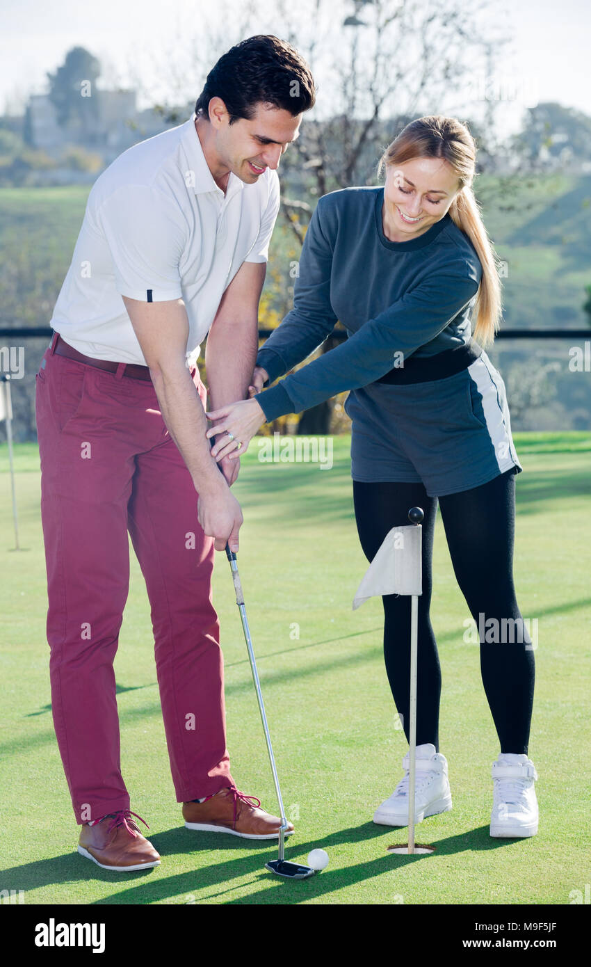Giovane donna insegna all uomo di base colpi di golf Foto Stock