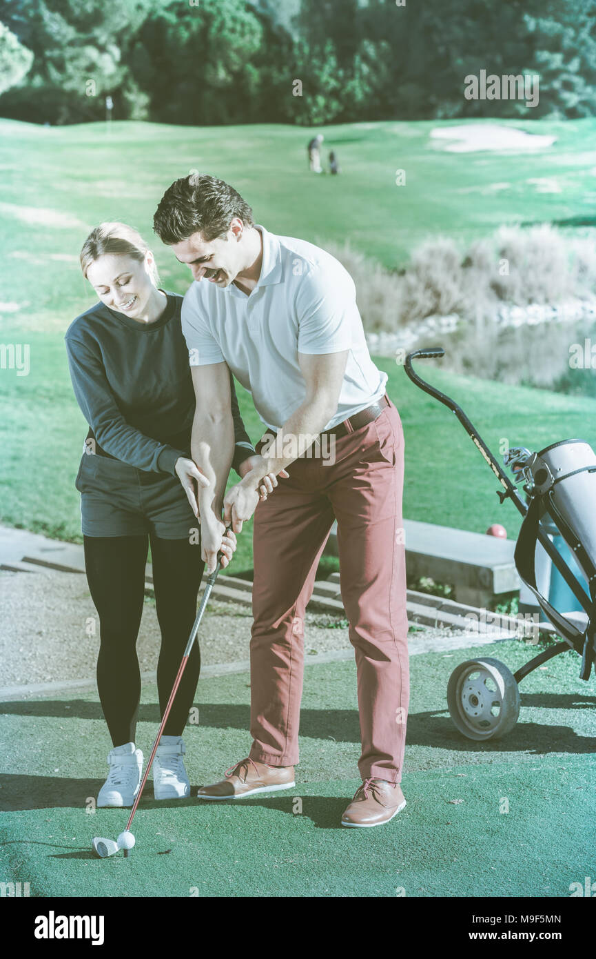 Femmina giocatore di golf mostra un uomo come mettere le mani quando hanno colpito la palla Foto Stock