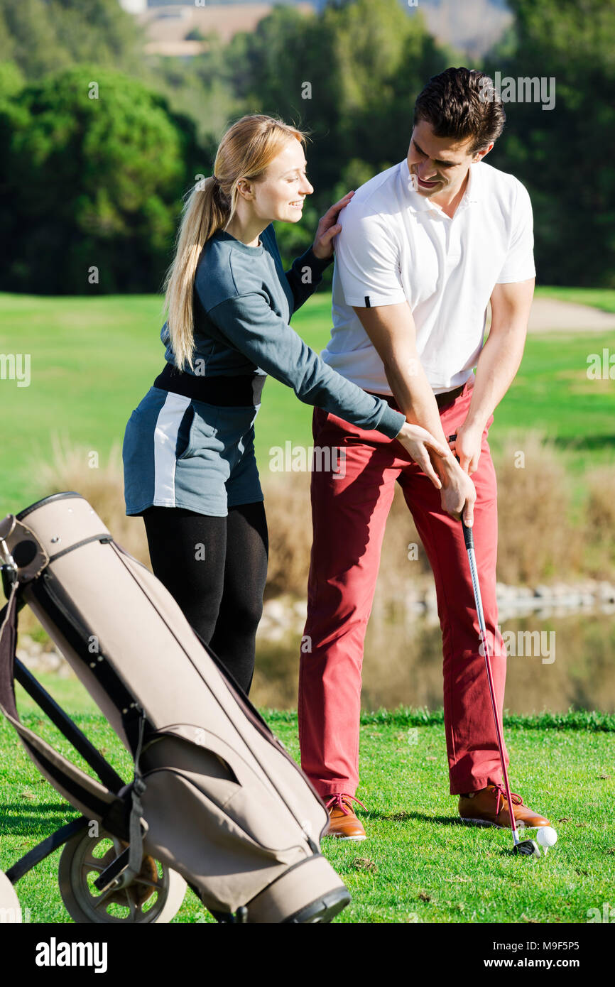 Positivo donna giovane golfista uomo di formazione per giocare a golf e colpire la sfera correttamente Foto Stock