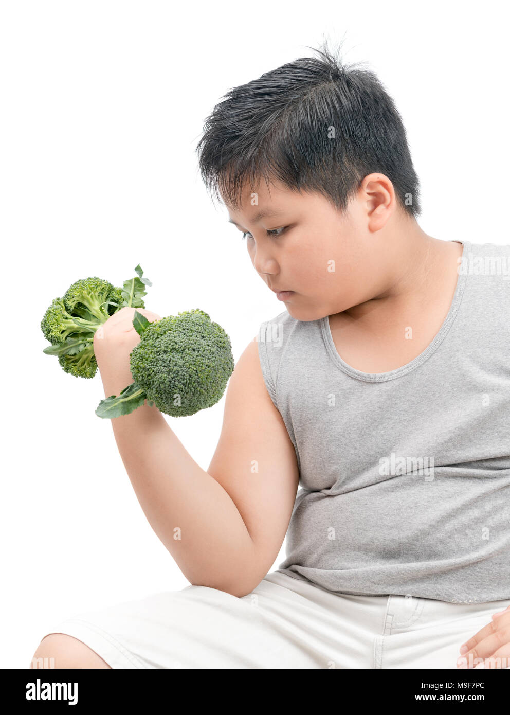 Obesi Fat Boy Tenendo un manubrio di broccoli isolati su sfondo bianco, dieta ed esercizio fisico per un buon concetto di salute Foto Stock