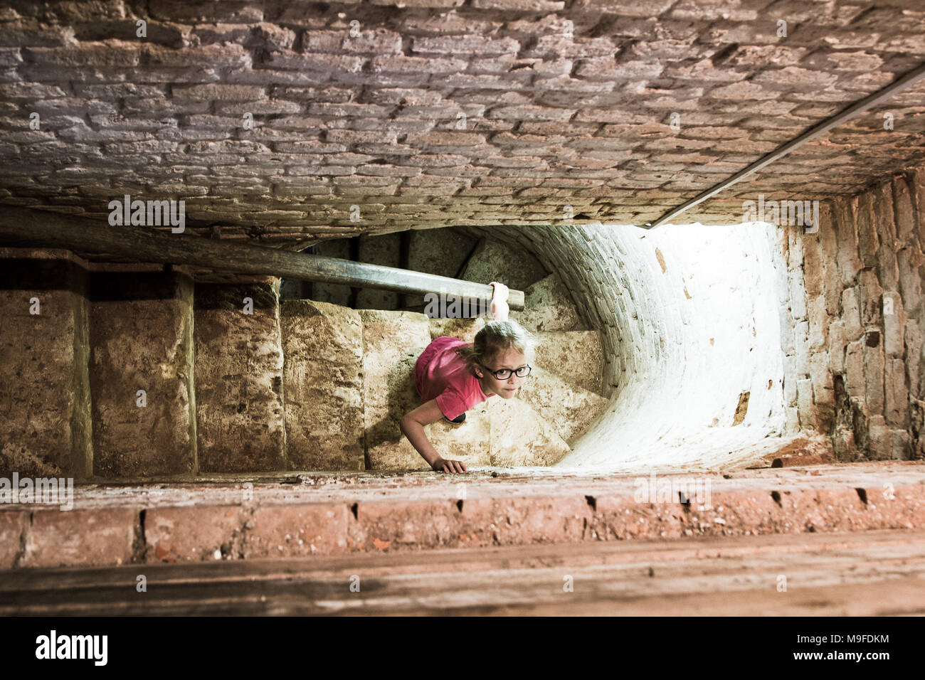 Bambina scende il vecchio stretta scalinata in pietra nella torre Foto Stock