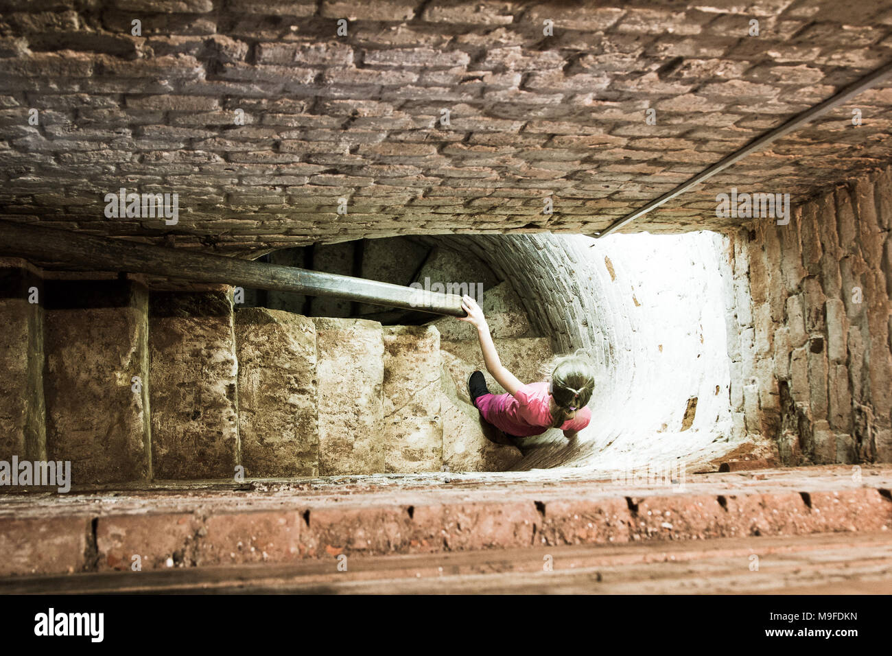 Bambina scende il vecchio stretta scalinata in pietra nella torre Foto Stock