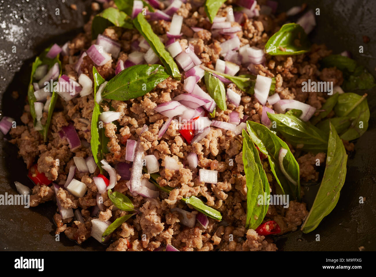 Larb, il Thai di maiale e insalata di erbe in un nero wok in acciaio Foto Stock