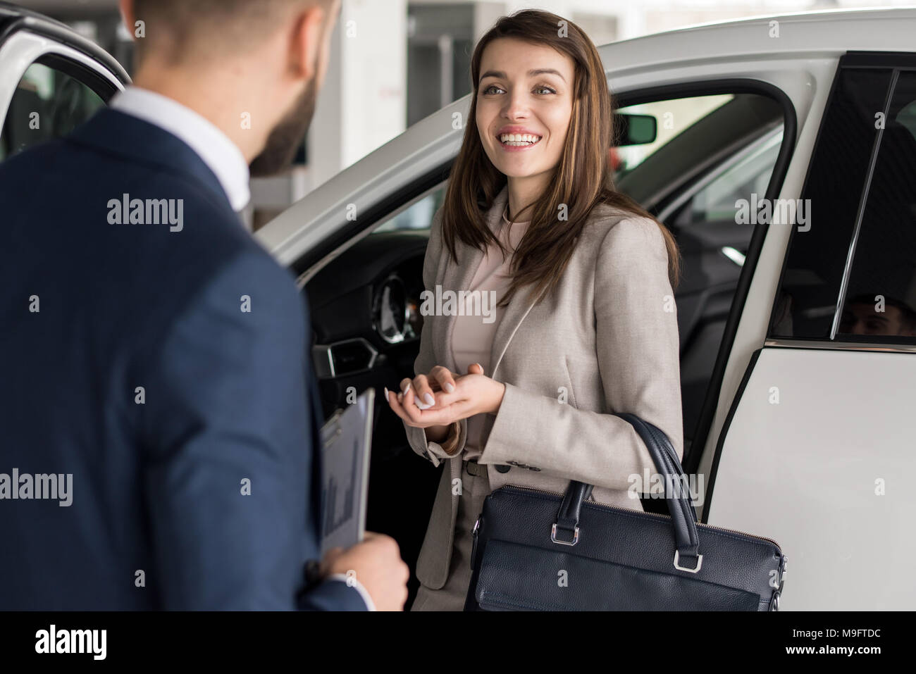 Donna felice la scelta di auto in showroom Foto Stock