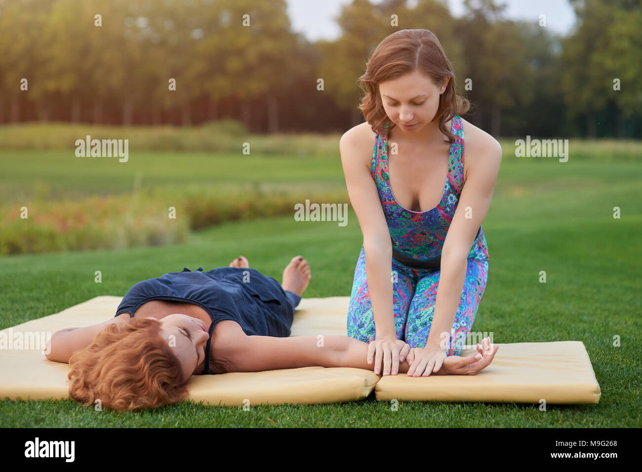 Braccio di massaggio all'aperto. Thai yoga massaggio del braccio sul tappeto  nel parco Foto stock - Alamy