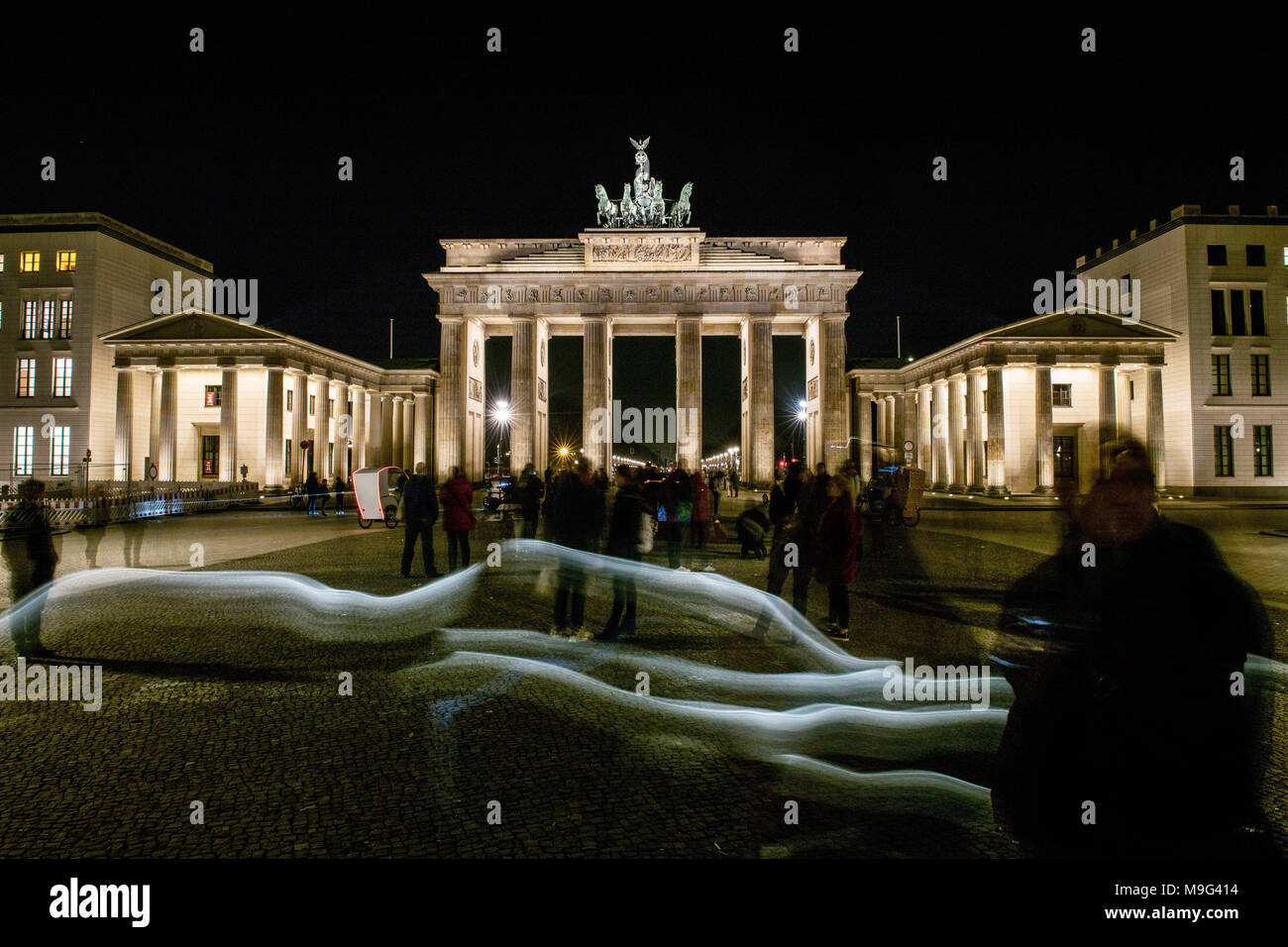 24 marzo 2018, Germania Berlino: la Porta di Brandeburgo è illuminata di notte whilestrollers passanti. Questo è stato disposto entro un'azione denominata "Earth Hour' dove le luci si sono spente. L'organizzazione ambientale WWF vuole aumentare la consapevolezza sul cambiamento climatico. Foto: Paolo Zinken/dpa Foto Stock