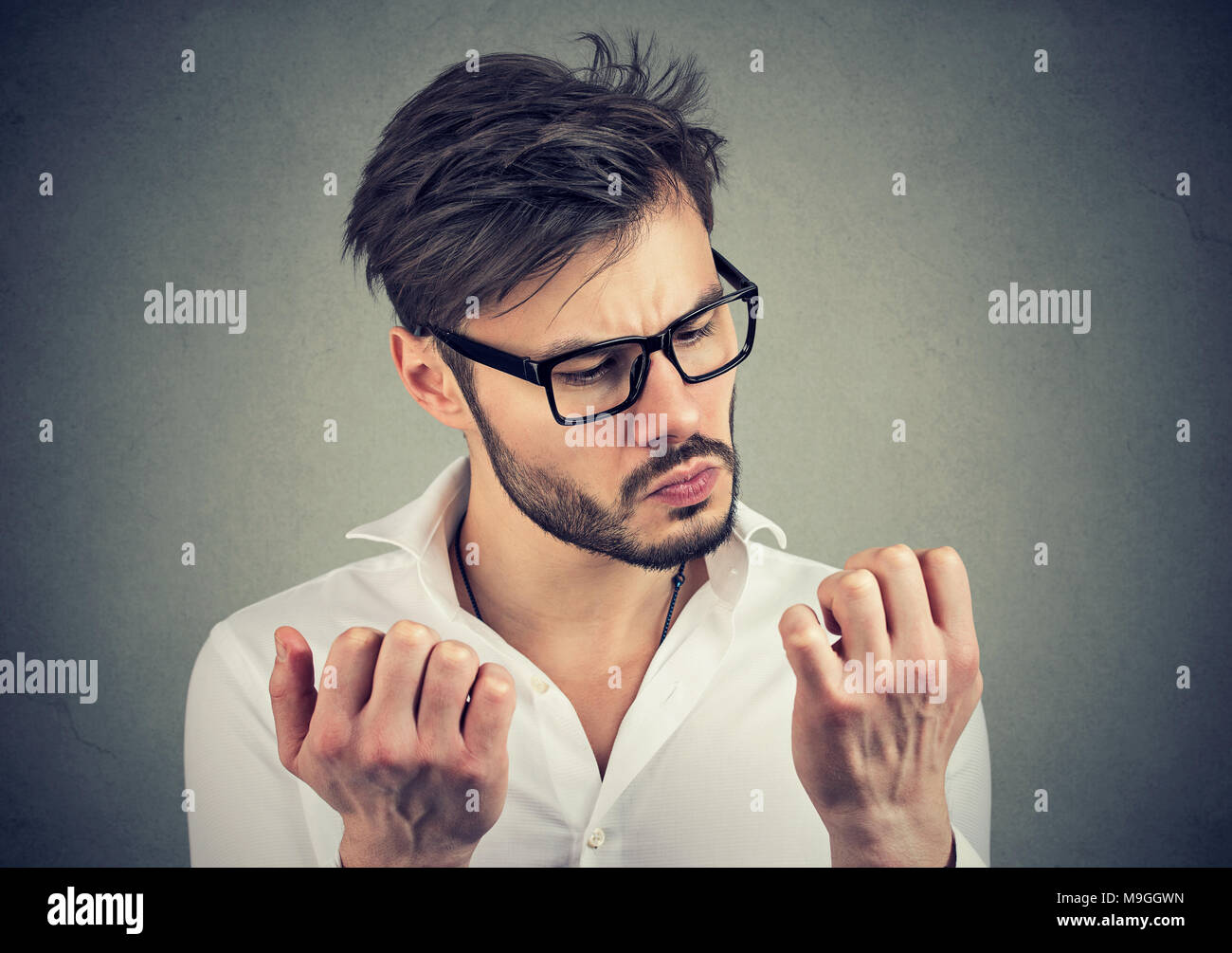 Giovane uomo serio con disturbo ossessivo compulsivo esplorando la pulizia delle mani. Foto Stock