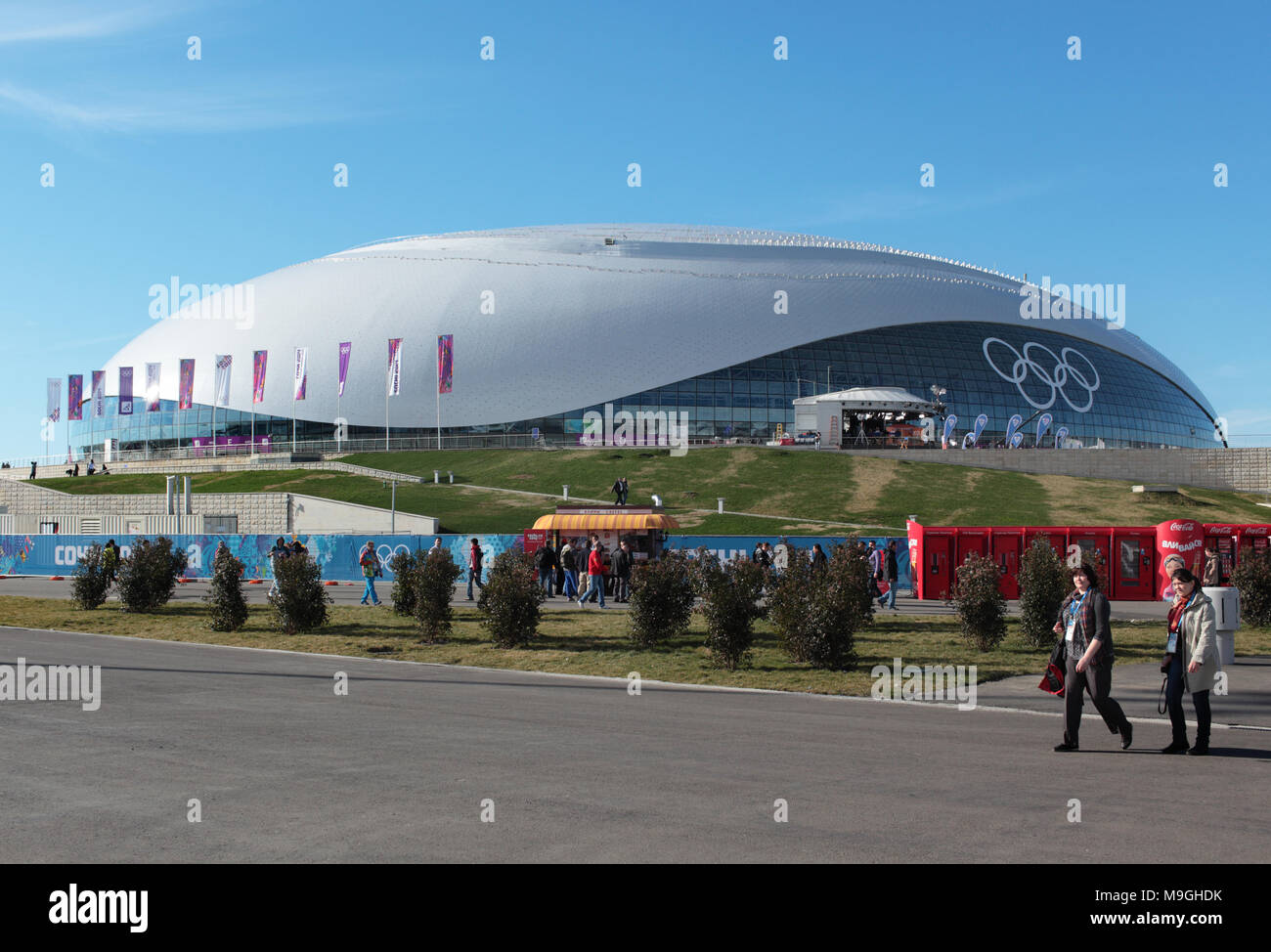 Sochi, Russia - 12 Febbraio 2014: la gente camminare contro il Bolshoy Cupola di ghiaccio nel Parco Olimpico. Questo sport venue ospitato gare di hockey su ghiaccio di Foto Stock