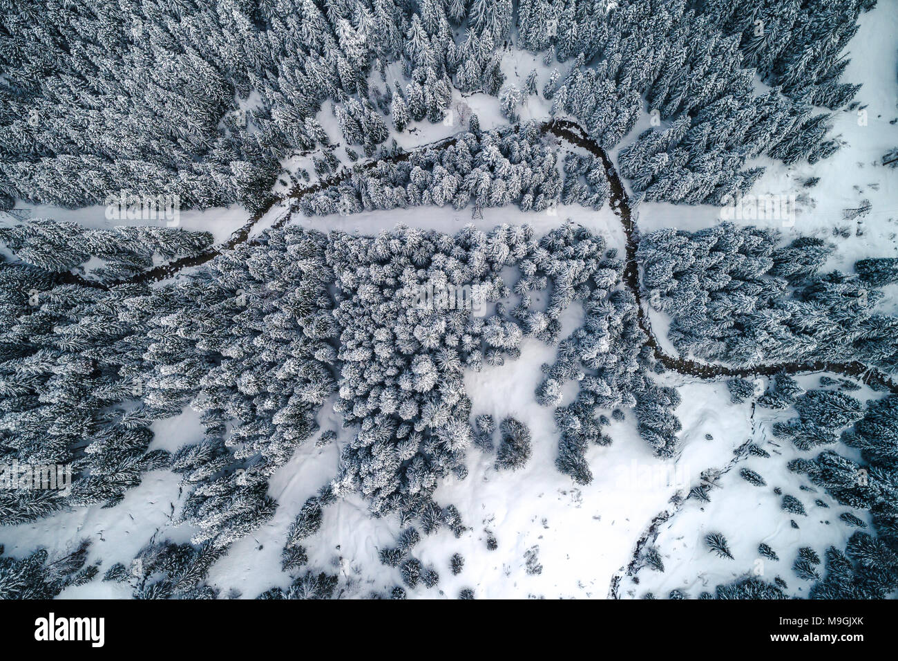 Elicottero Overehad angolo di antenna di coperta di neve valle di montagna con stream e linee elettriche Foto Stock