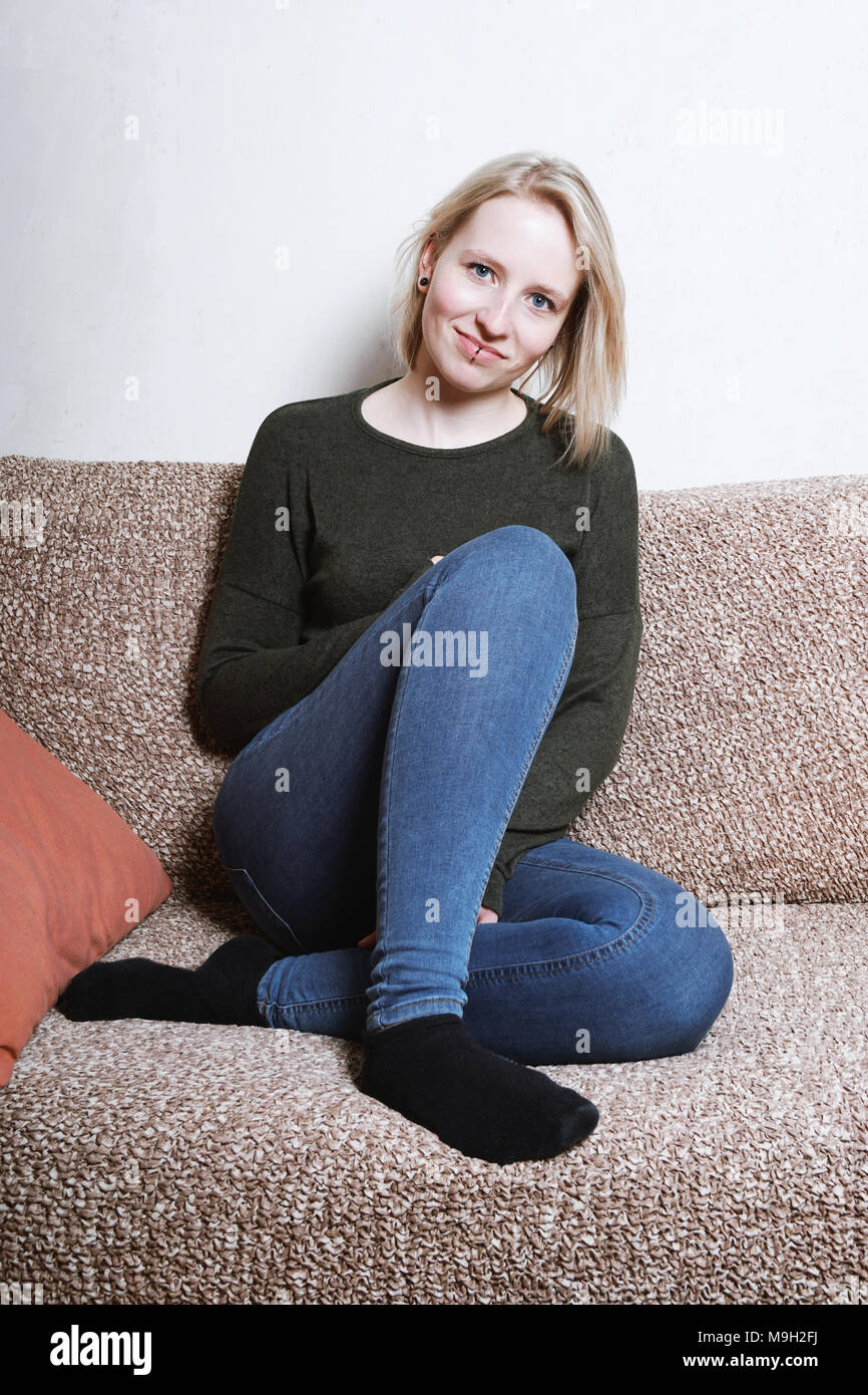 Giovane donna seduta sul divano di casa Foto Stock