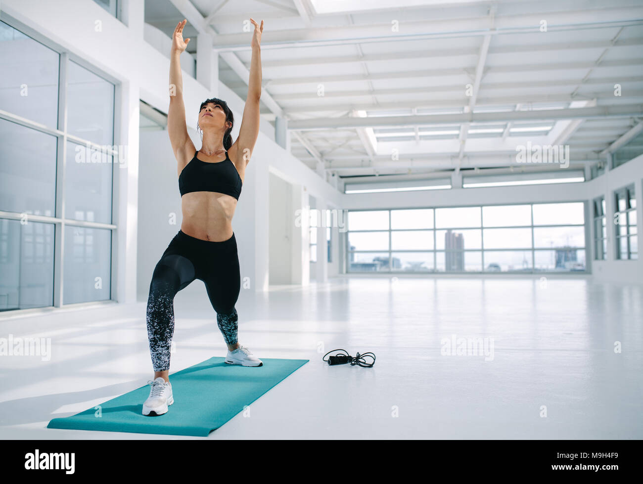 Attenti alla salute della donna a praticare yoga lunge con tratto ascendente pongono, Virabhadrasana in fitness studio. Femmina caucasica esercizio di yoga in palestra. Warr Foto Stock