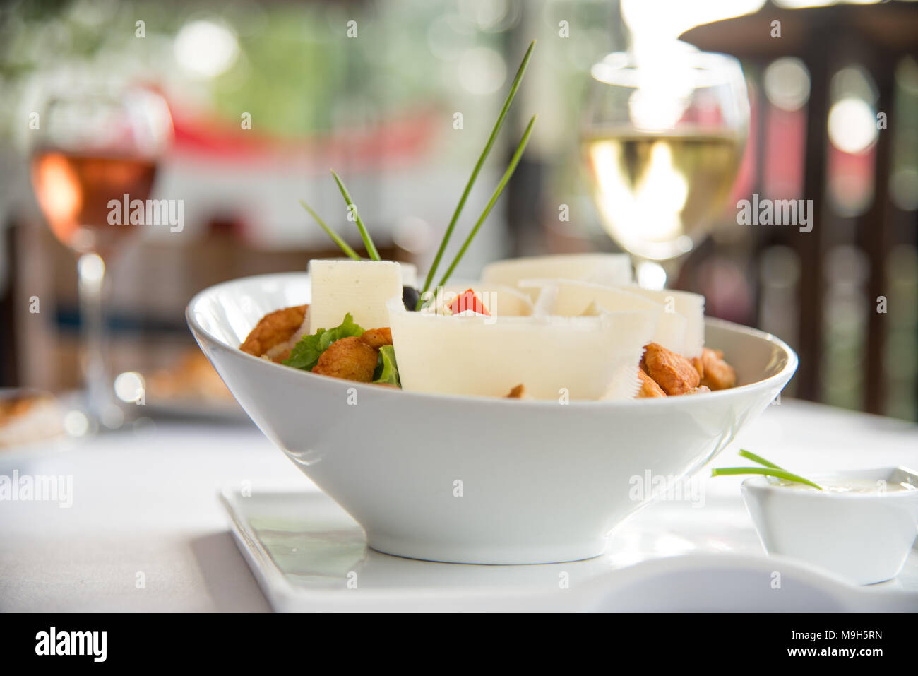 Bellissimo colpo di guarnito insalata. Due bicchieri di vino in background. Il ristorante perfetto shot per pranzo foto. Foto Stock