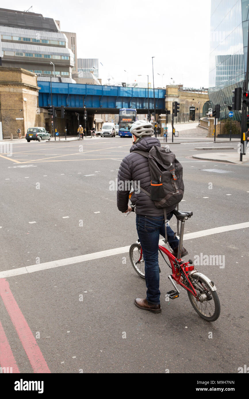 Pilota di un Brompton bicicletta pieghevole in corrispondenza della giunzione di Stamford Street e Blackfriars Bridge a sinistra. London REGNO UNITO Foto Stock