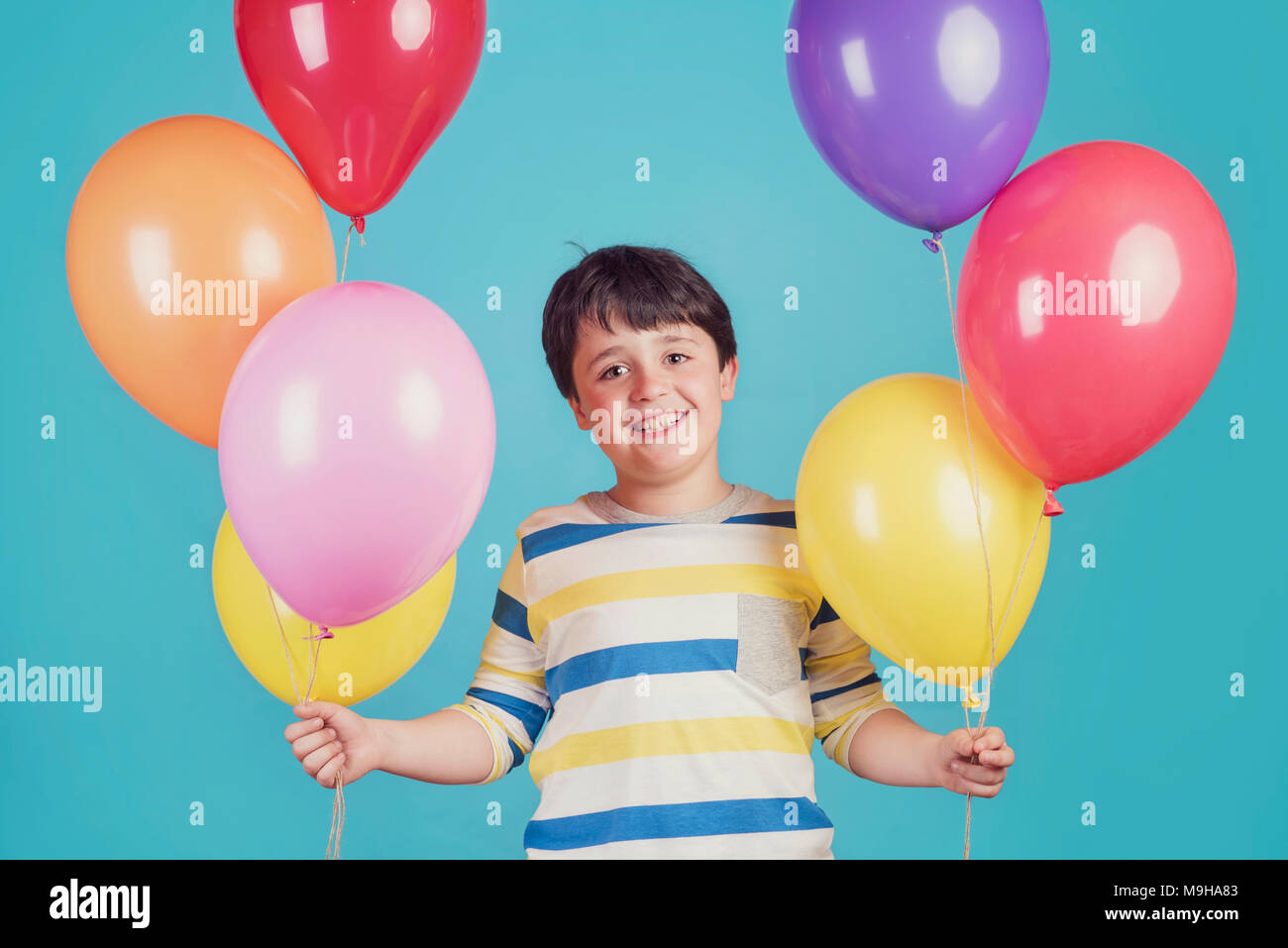 Felice e sorridente ragazzo con palloncini colorati Foto Stock