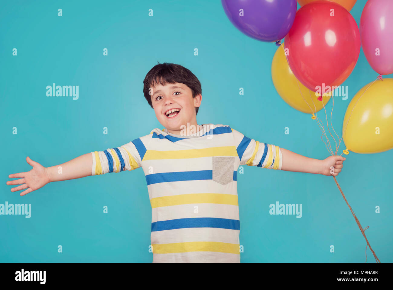 Felice e sorridente ragazzo con palloncini colorati Foto Stock