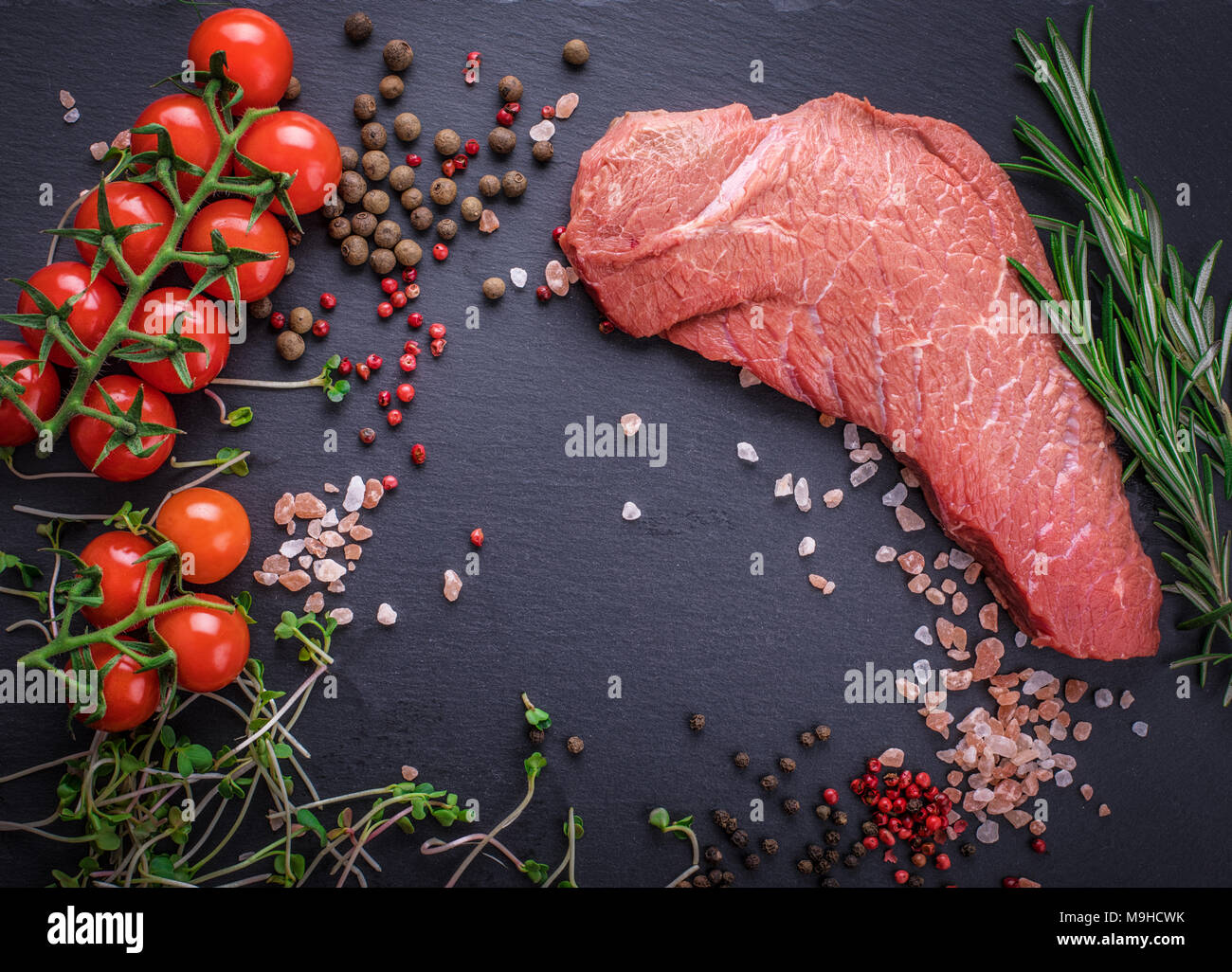 Uno sfondo con un pezzo grezzo di manzo e verdure, un processo di cottura di carne con verdure Foto Stock