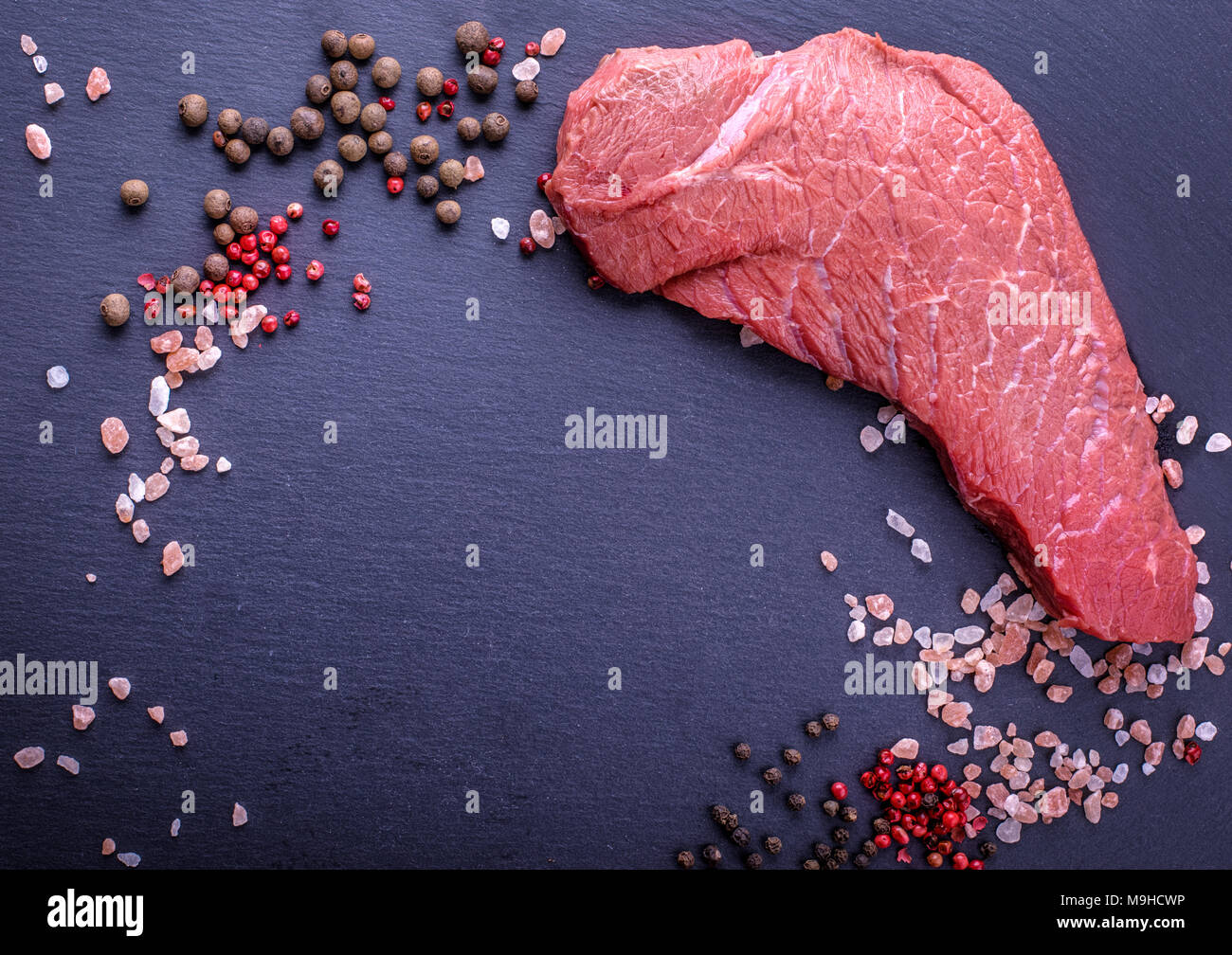 Uno sfondo con un pezzo grezzo di manzo e verdure, un processo di cottura di carne con verdure Foto Stock