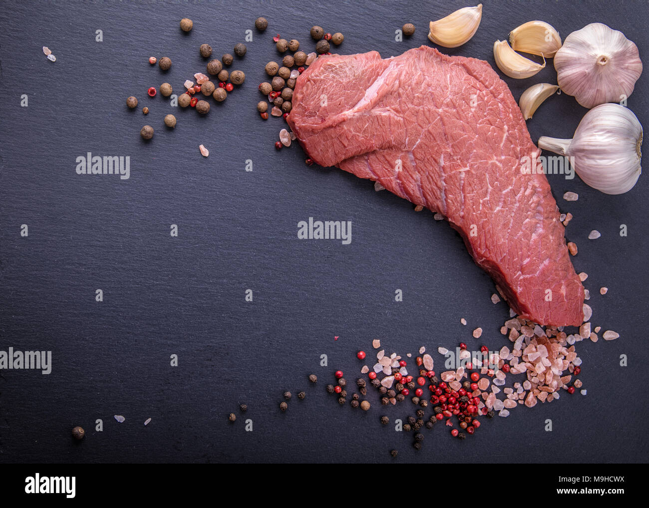 Uno sfondo con un pezzo grezzo di manzo e verdure, un processo di cottura di carne con verdure Foto Stock