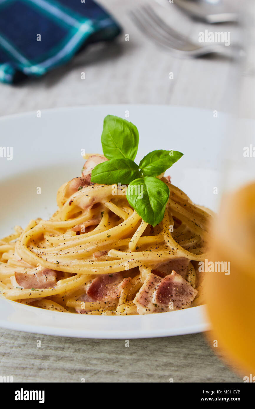 Spaghetti alla carbonara sulla piastra bianca con foglie di basilico Foto Stock