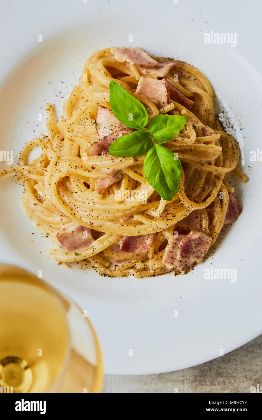 Spaghetti alla carbonara sulla piastra bianca con foglie di basilico Foto Stock