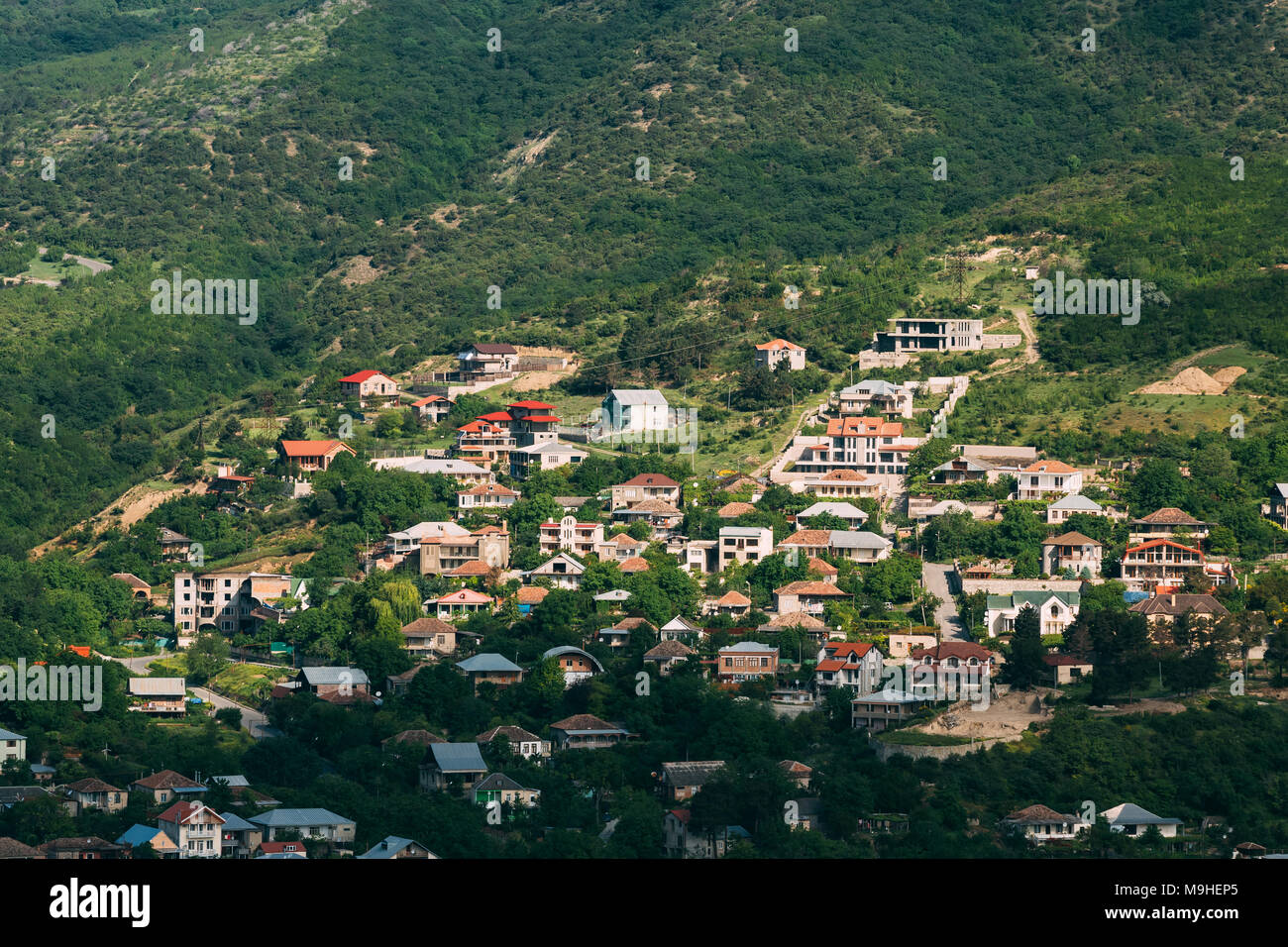 Mtskheta, Georgia. Vista superiore del nuovo eretto Bungalow villaggio, circondato dalla zona residenziale del periodo sovietico sul verde collina in estate Sunny Foto Stock