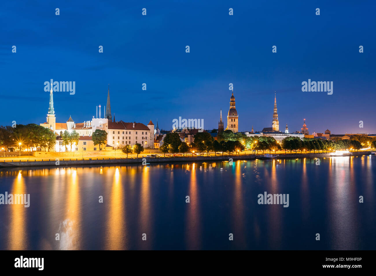 Paesaggio urbano di sera di Riga, Lettonia. Vista notturna con il blu del cielo. Copyspace. Nessuno. Vista urbano. Vista notturna del castello, la cattedrale e la chiesa di San Pietro Foto Stock