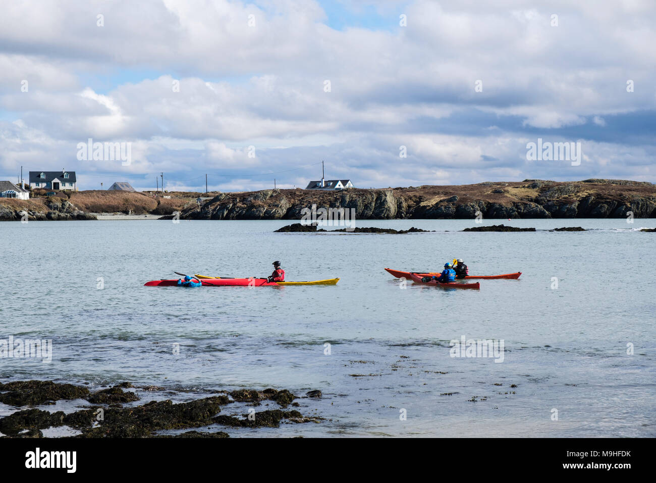 Kayakers kayak in kayak da mare nella baia di Borthwen. Rhoscolyn, Isola Santa, Isola di Anglesey, Galles del Nord, Regno Unito, Gran Bretagna Foto Stock
