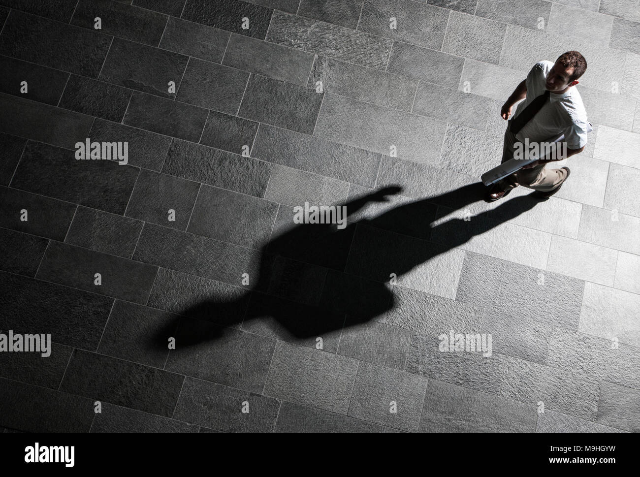 Vista da sopra di un imprenditore camminare sul piano della lobby e un shawdow sul pavimento. Foto Stock